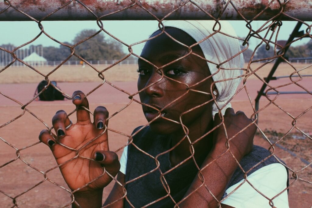 black woman with headscarf behind fence