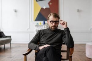 man in black sweater sitting on brown wooden chair