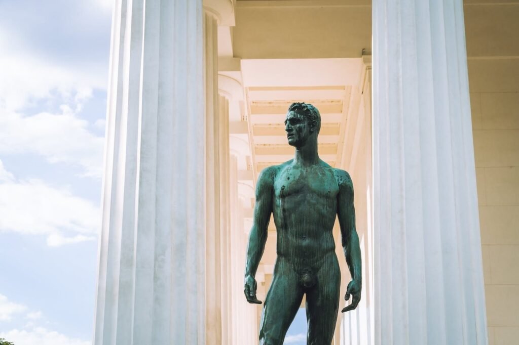 statue of nude man between columns of buildings