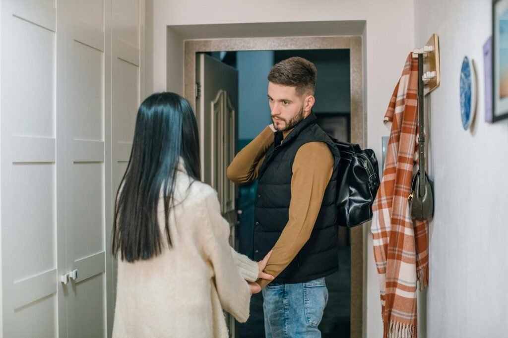 a person in cream sweater holding the hand of a man near the doorway